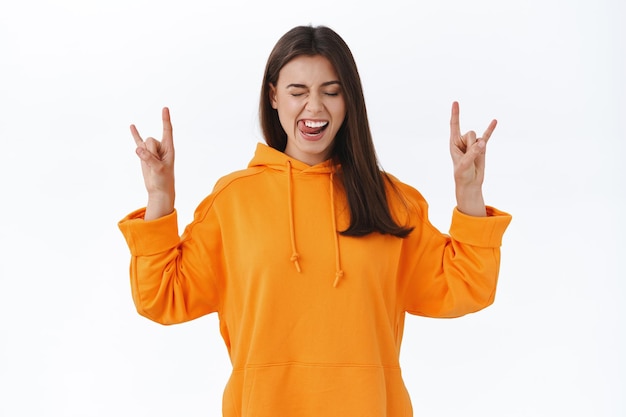 Yeah rock n roll. Excited happy young woman having fun at concert, scream at music festival close eyes and make heavy metal gesture