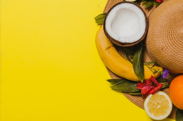 Free photo yellow background with hat and fruits