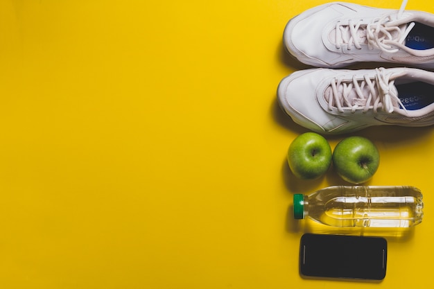 Желтый фон с мобильным телефоном, кроссовки и яблоки