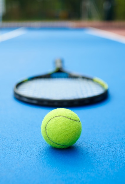 Бесплатное фото Желтый мяч лежит на синем ковре теннисного корта с профессиональной ракеткой.