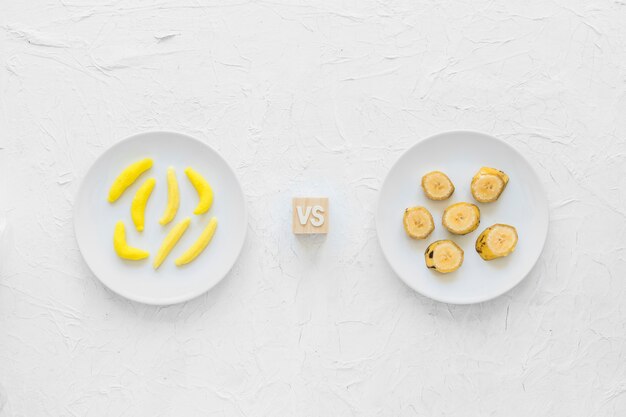 노란 바나나 모양의 질감 된 배경 위에 접시에 바나나 조각 대 껌 사탕
