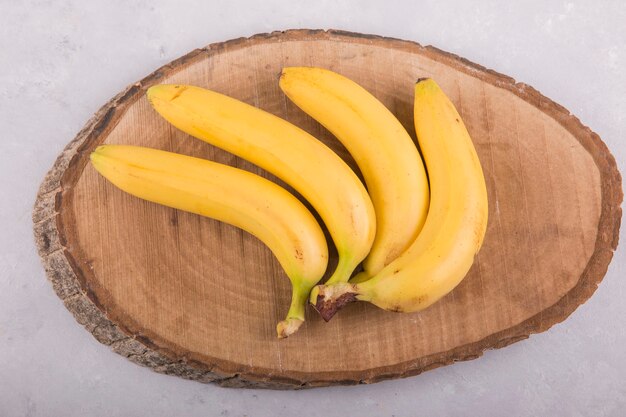 Yellow bananas bunch isolated on concrete background on a piece of wood