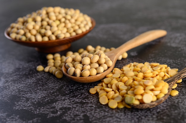 Yellow beans in a wooden bowl and wooden spoon on the black cement floor.