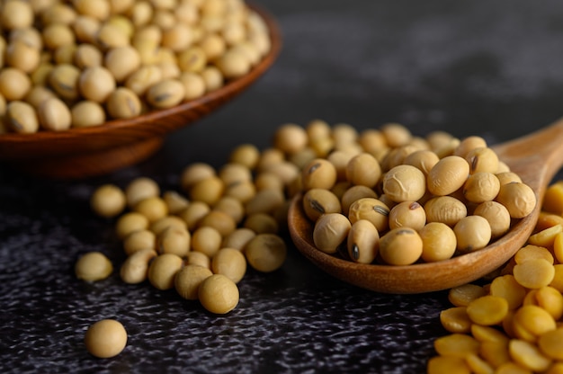 Free photo yellow beans in a wooden bowl and wooden spoon on the black cement floor.