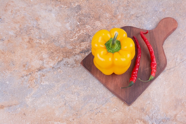 Желтый болгарский перец с красным перцем чили на деревянном блюде