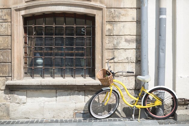 Yellow bicycle with basket in front of old wall