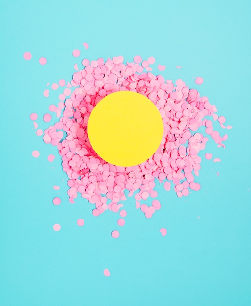 Yellow blank circle frame over the festive small pink confetti against blue background