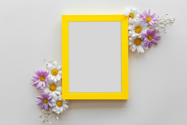 Foto gratuita cornice bordo giallo decorata con bellissimi fiori contro superficie bianca