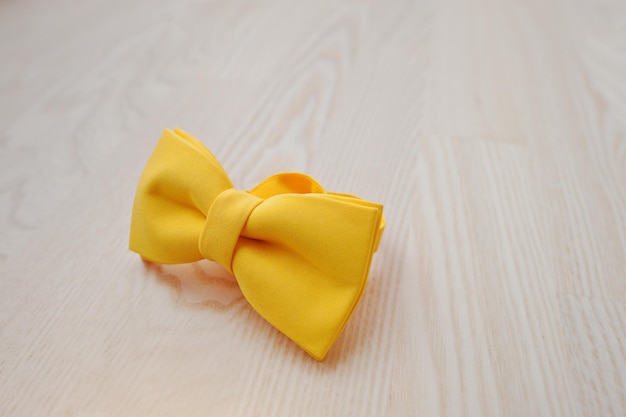 Yellow bow tie on light wooden background