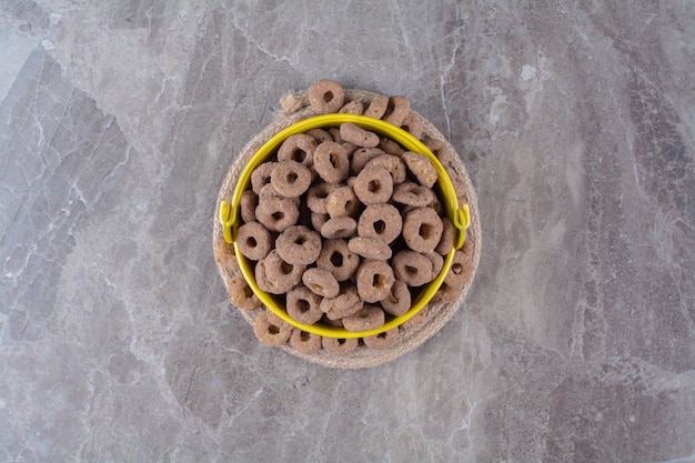 A yellow bucket full of healthy tasty cereals on sackcloth .