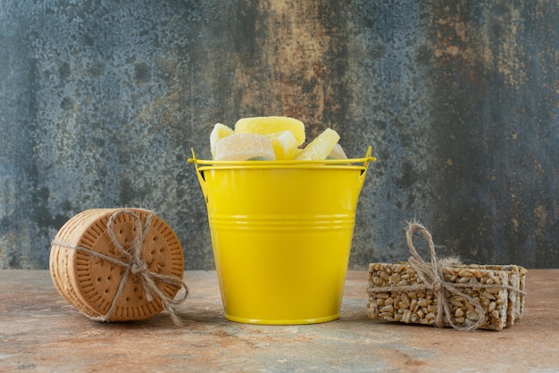 A yellow bucket of marmalade with cookies and peanut brittles