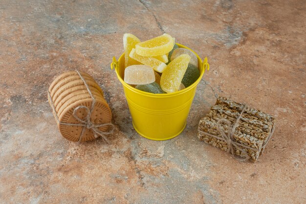 A yellow bucket of marmalade with cookies and peanut brittles