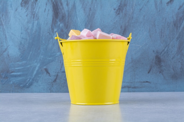 Free photo an yellow bucket of pink and yellow sweet confectionery pastila