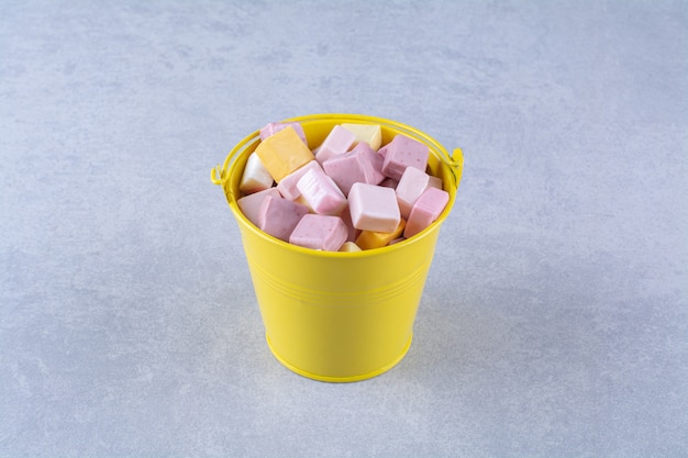 An yellow bucket of pink and yellow sweet confectionery pastila