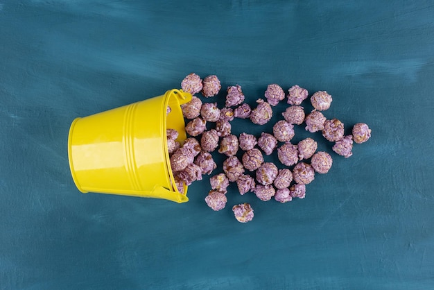 Yellow bucket with popcorn candy spilled over on blue