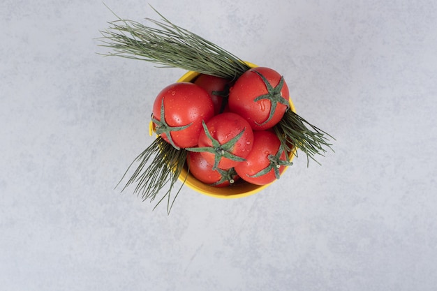 Yellow bucket with tomatoes on dark background