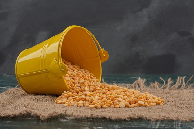 Free photo yellow bucket with wheat on burlap on marble surface