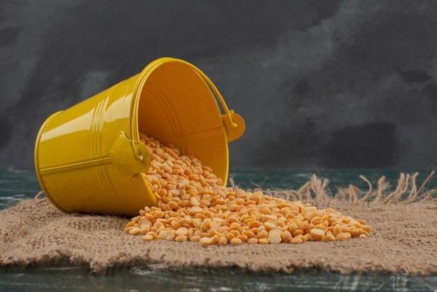 Yellow bucket with wheat on burlap on marble surface