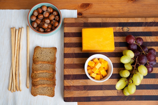 Yellow cheese and grapes laying on wooden board