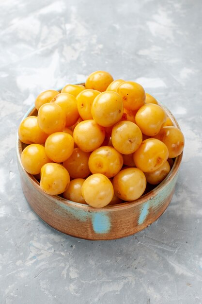 yellow cherries inside bowl on grey desk