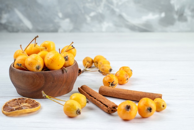Free photo yellow cherries mellow and fresh along with cinnamon on light