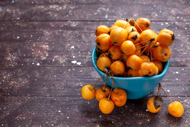 yellow cherries mellow fresh and ripe inside blue bowl on brown wooden desk