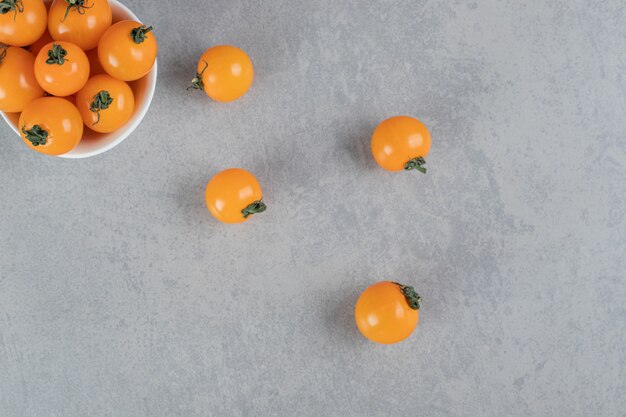 Yellow cherry tomatoes isolated on concrete surface