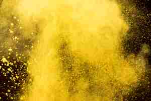 Free photo yellow cloud of cosmetic powder on black background