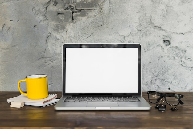 Yellow coffee mug and open laptop with office supplies on wooden table