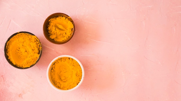 Free photo yellow color powder in the different type of bowls on colored backdrop