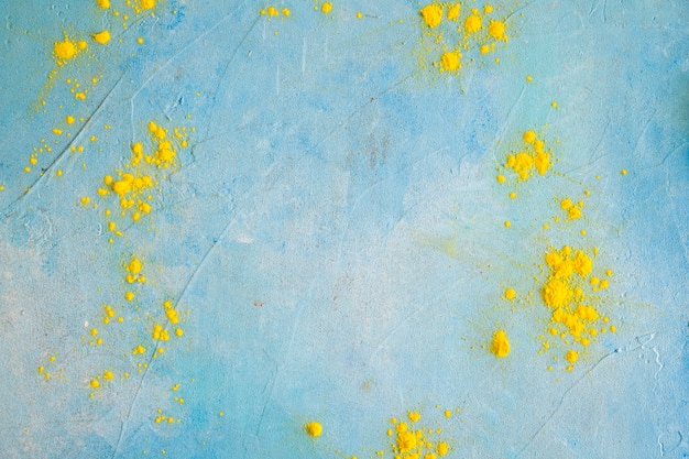 Free photo yellow color powder on painted blue wall