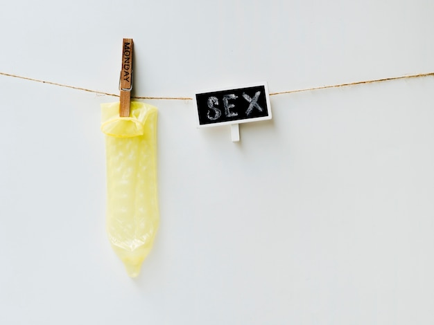 Yellow condom on clothesline with white background