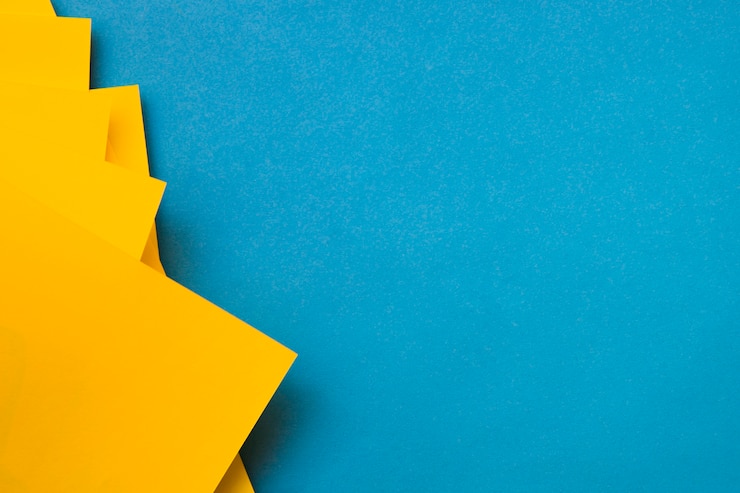 Free Photo yellow craftpapers on blue backdrop