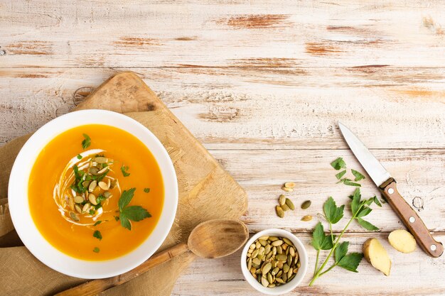 Yellow cream soup with seeds and knife beside