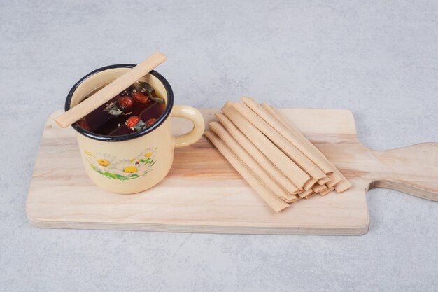 A yellow cup with sweet sticks on wooden board . High quality photo