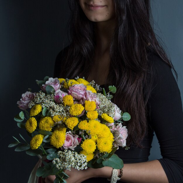 Yellow daisies and pink roses promoted by a woman