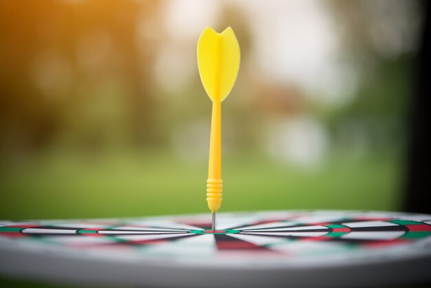 Yellow dart arrow hitting in the center of dartboard.