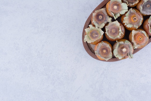 Free photo yellow date plums in a wooden platter on grey.