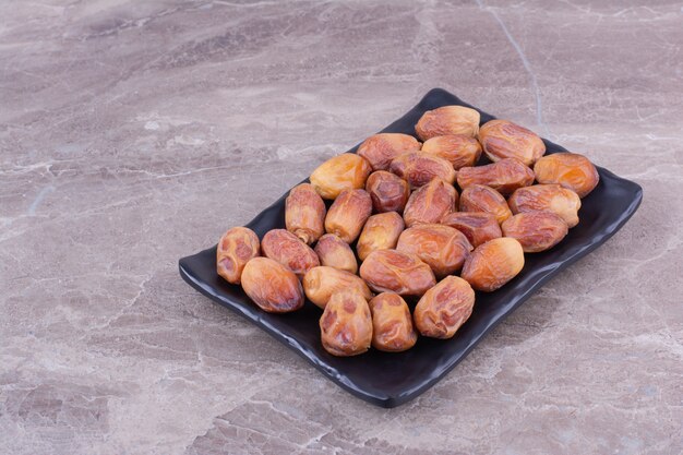 Yellow dates in a black ceramic platter.