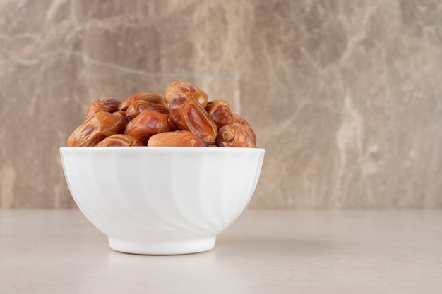 Free photo yellow dry dates in a ceramic bowl.