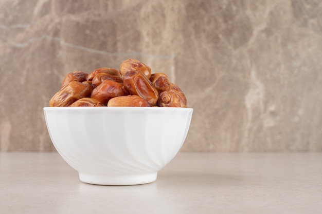 Yellow dry dates in a ceramic bowl.