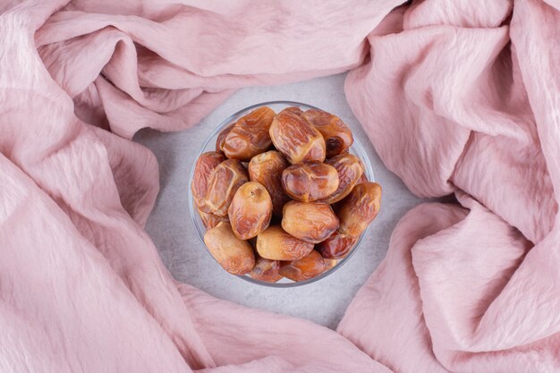 Free photo yellow dry dates in a cup on concrete surface