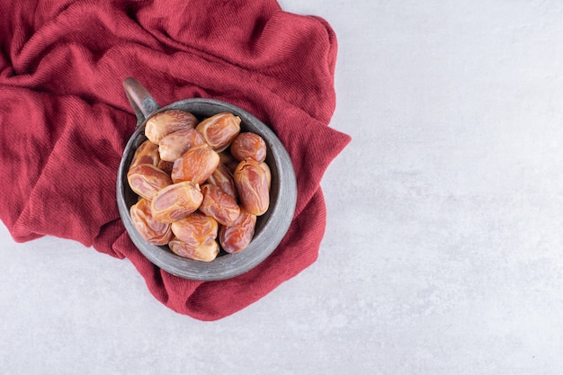 Yellow dry dates in a cup on concrete surface