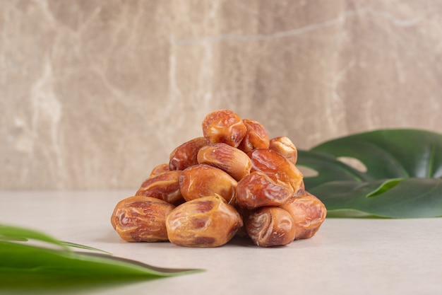 Yellow dry dates isolated on concrete around green leaves.