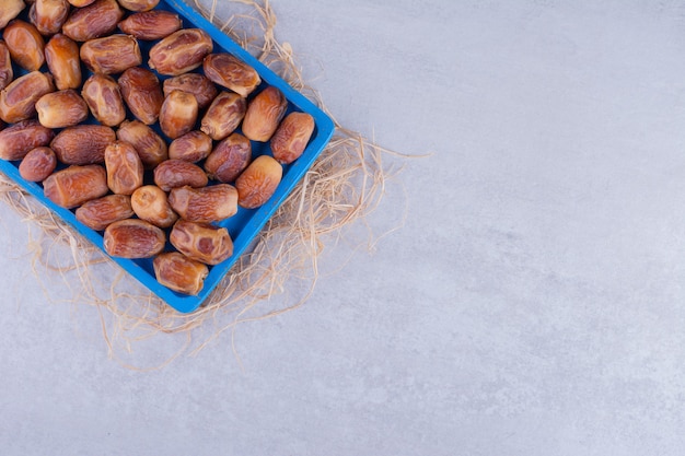 Yellow dry dates on a platter on concrete surface