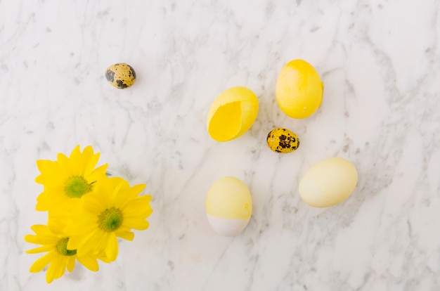 Yellow Easter eggs near fresh flowers