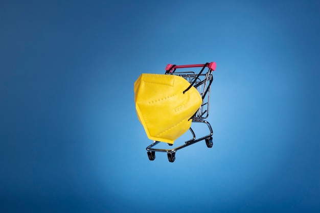 Бесплатное фото Желтая маска ffp2 и корзина для покупок