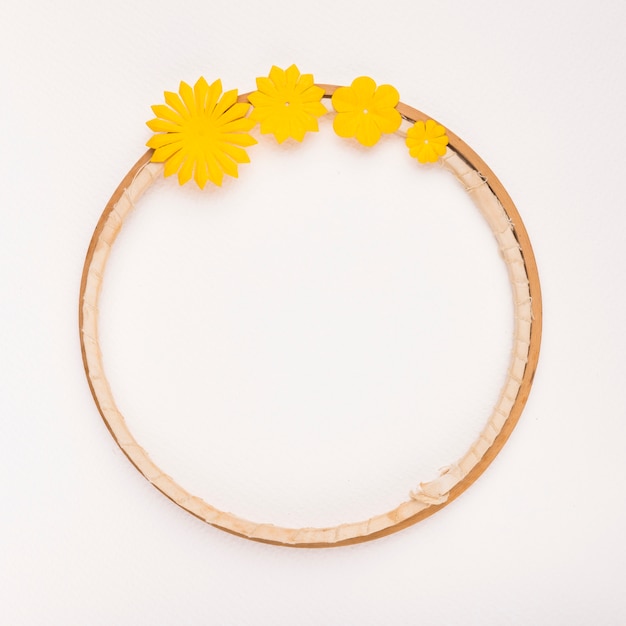 Yellow flowers decorated on circular wooden frame on white backdrop