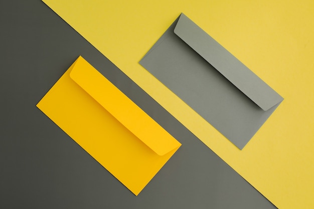 Yellow and gray paper envelopes on color paper background. top view.