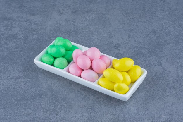 Yellow , green,and pink gums on the plate, on the marble background. 